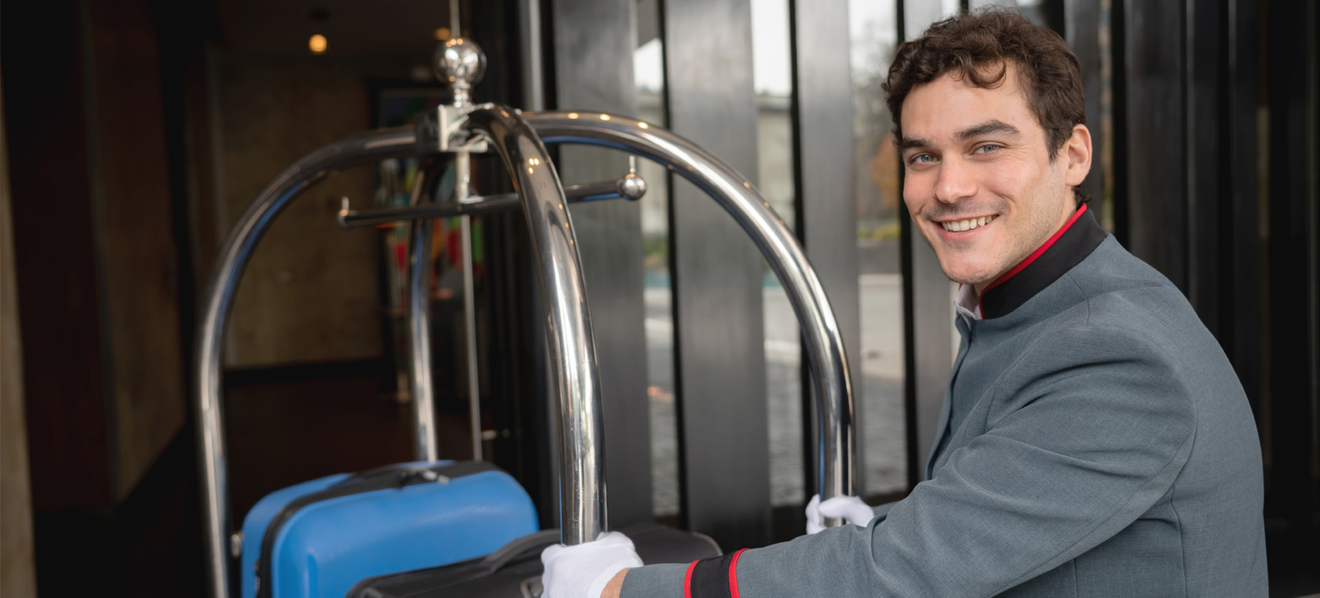 Image of hotel bellhop pushing luggage through a front door